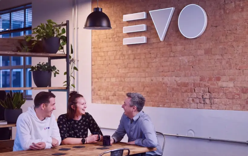 3 Evo Agency employees sitting at a table laughing