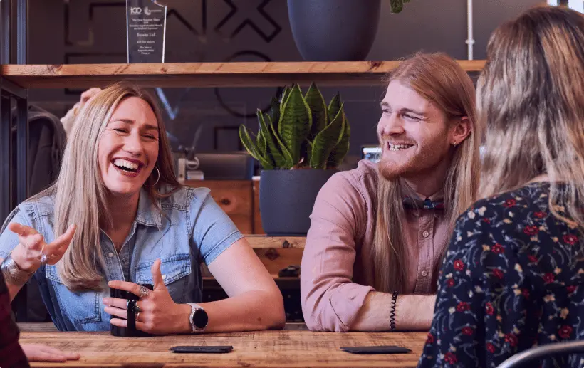 Evo Agency employees sitting at a table laughing and drinking coffee