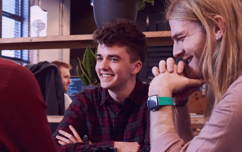 A close-up of two Evo Agency employees sitting together at a table laughing and smiling.