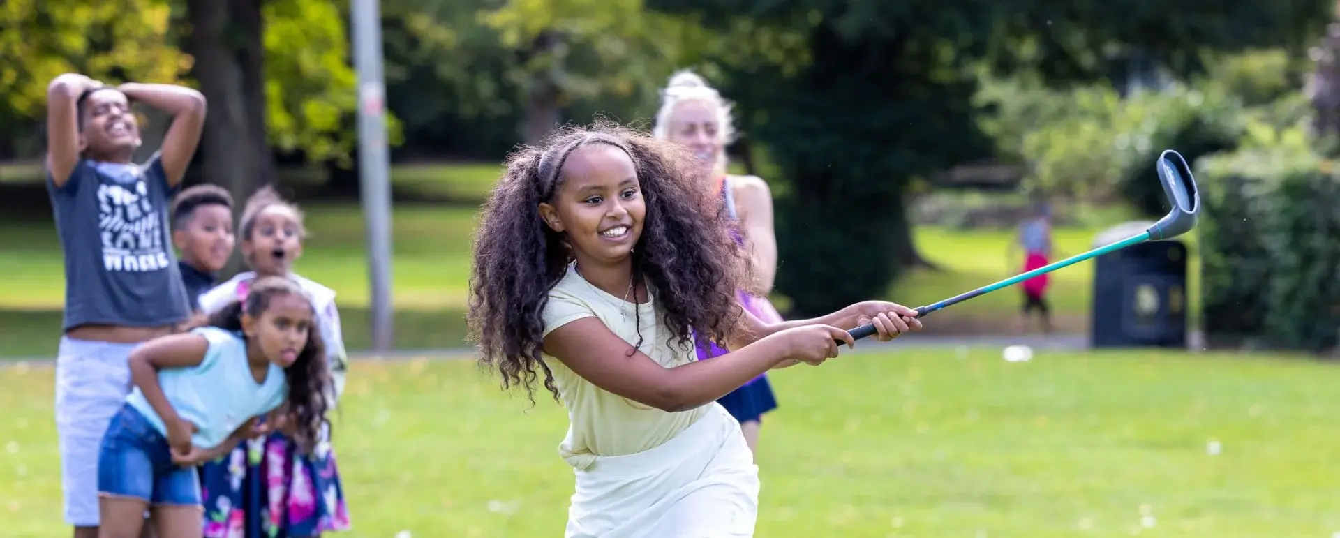 Girl looking pleased hitting a golf shot