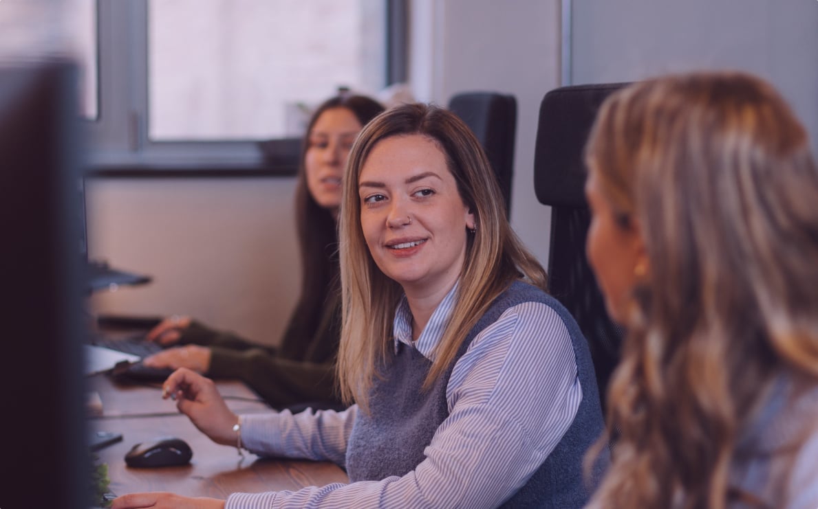 The paid search team at Evo Agency sitting at their desks talking to each other.